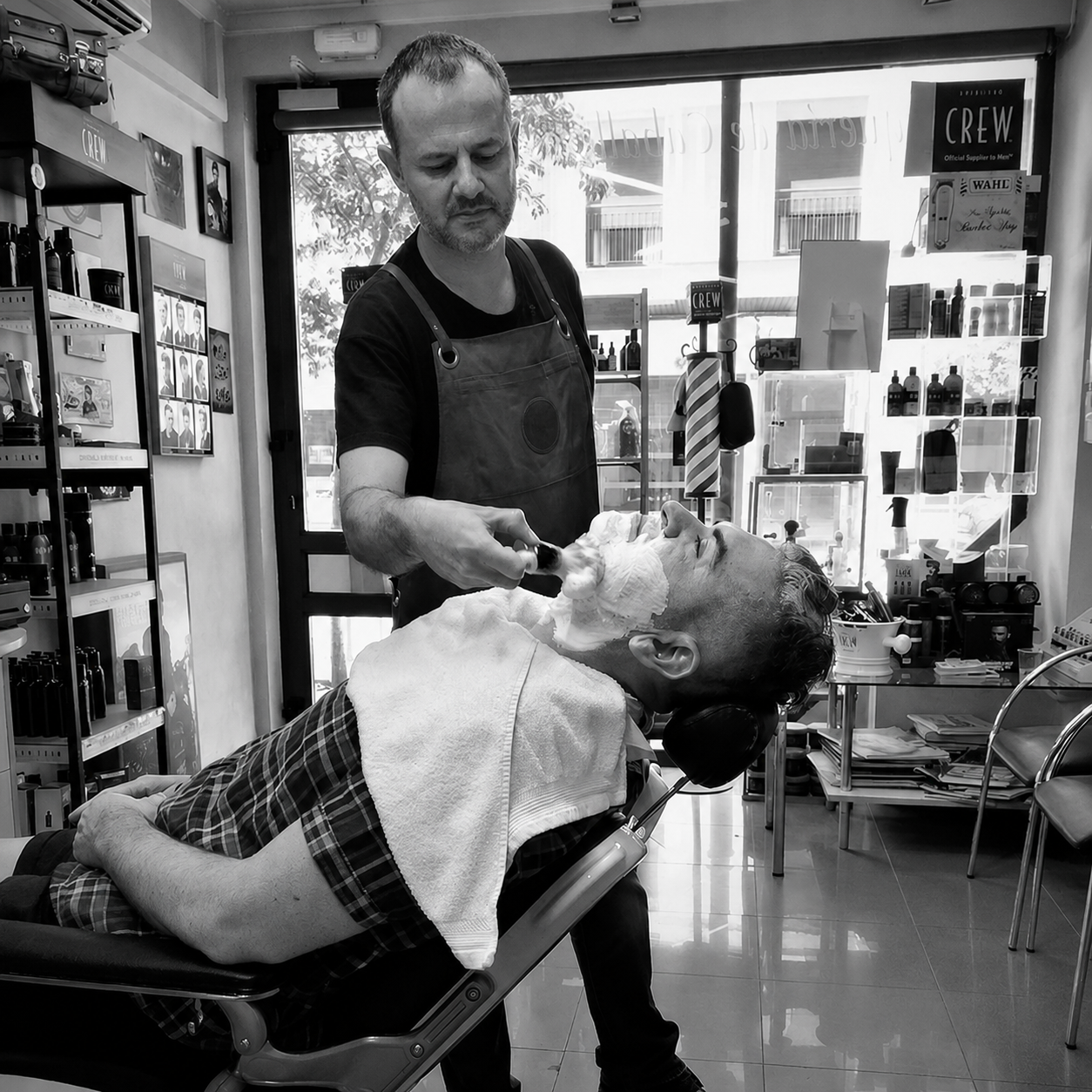 Nicolás afeitando a un cliente en la barbería de Albacete